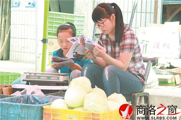 商州區(qū)楊斜鎮(zhèn)集市上，南思佳和妹妹在幫父母賣菜，閑暇之余，她們會(huì)拿起課外讀物翻一翻。在這個(gè)假期里，她們呆的最多的地方就是這個(gè)菜攤。